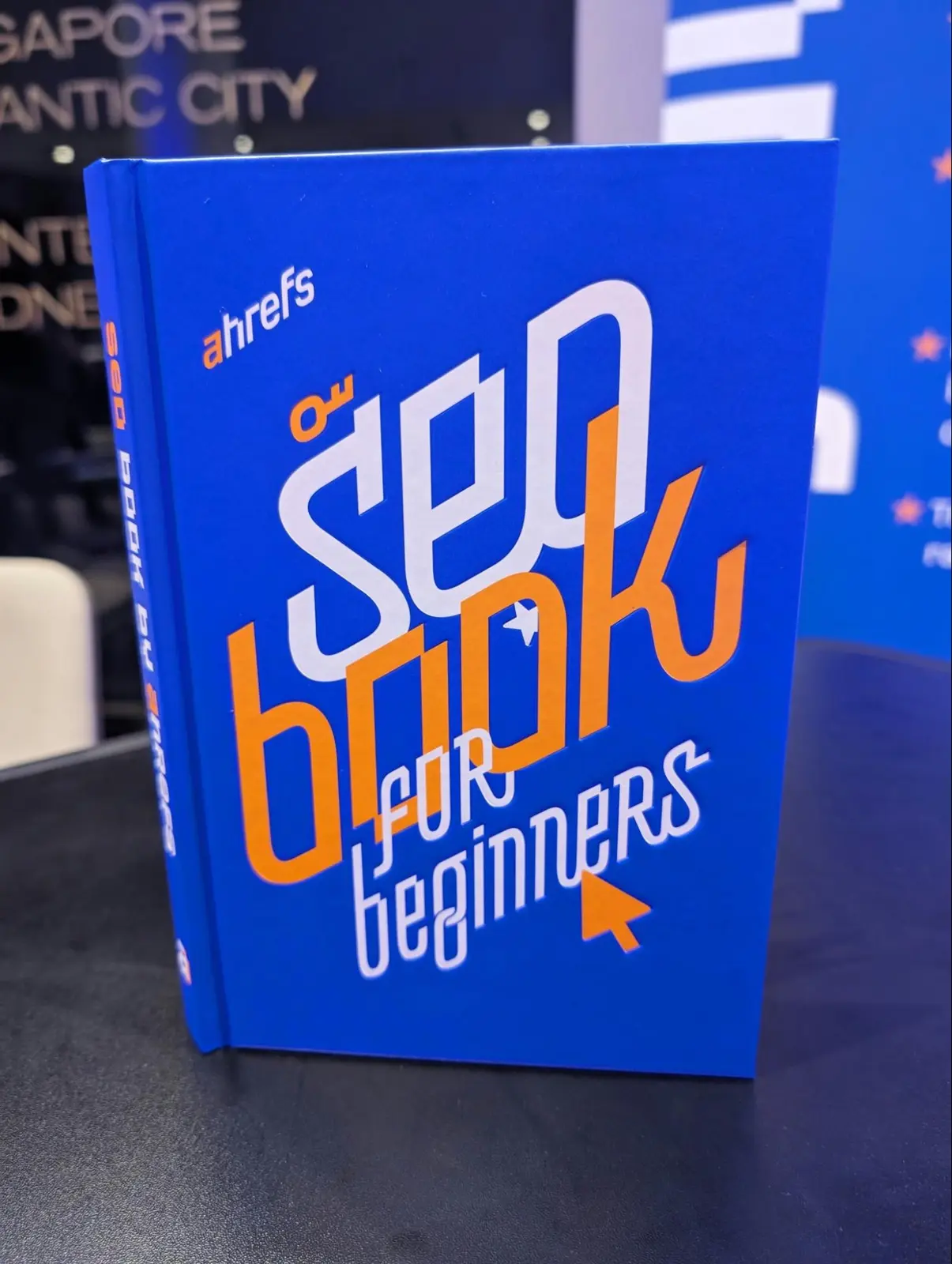 Ahrefs’ “SEO book for beginners”, with its blue cover, on a table at an event